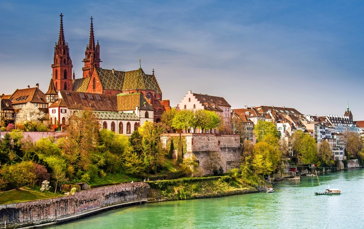Basel am Rheinufer mit der Basler Münster im Hintergrund an einem sonnigen Tag.