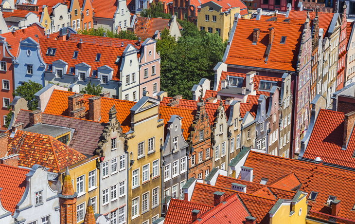 Bunte historische Häuser mit roten Dächern in einer europäischen Stadt aus der Vogelperspektive.