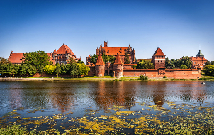 Burg Marienburg mit Wassergraben und klarer Himmel.