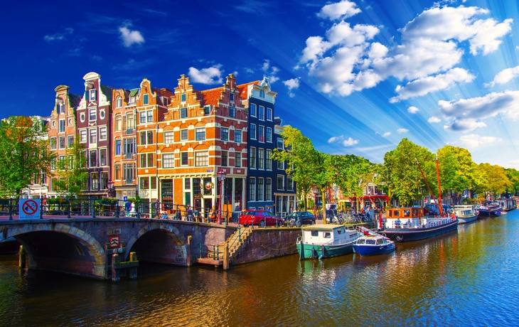 Kanallandschaft mit historischen Häusern und Booten bei Sonnenschein in Amsterdam.