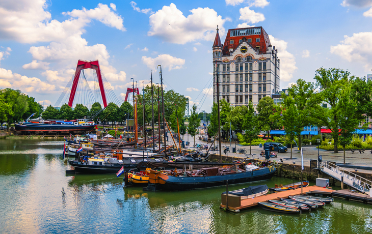 Historischer Hafen mit Segelbooten und historischem Gebäude im Hintergrund.