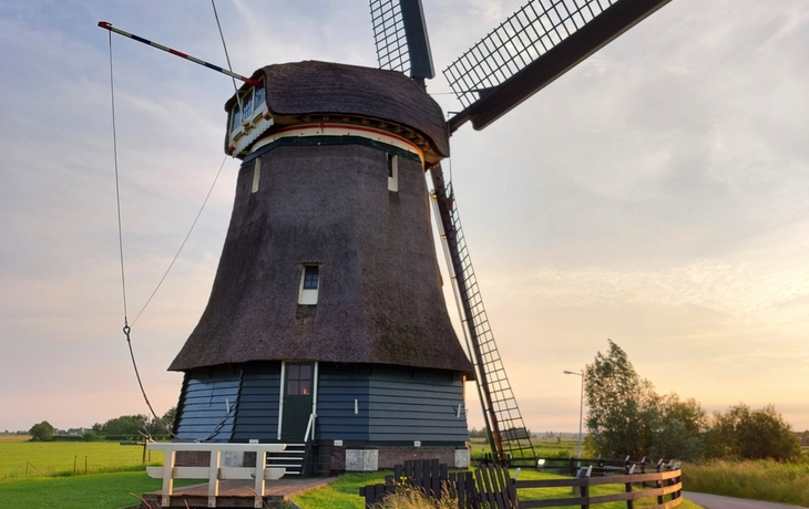 Windmühle in ländlicher Umgebung bei Sonnenuntergang.