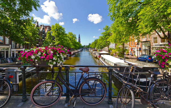Fahrrad auf Brücke mit Blumenkästen, Blick auf Kanal und Gebäude in Amsterdam.