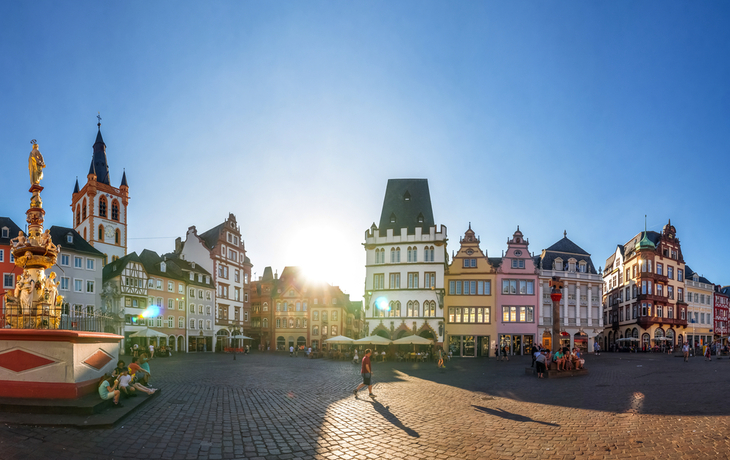 Panorama von einem sonnigen Marktplatz mit historischen Gebäuden und Brunnen.