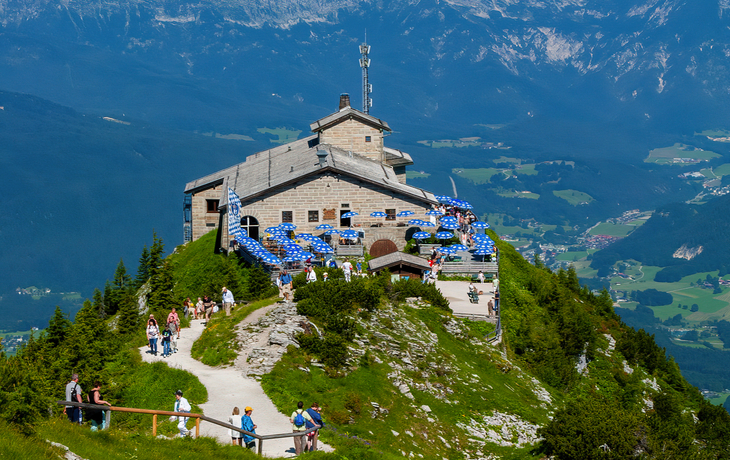 Gebirgsrestaurant auf Bergspitze mit weitläufigem Panoramablick und Besuchern im Freien.