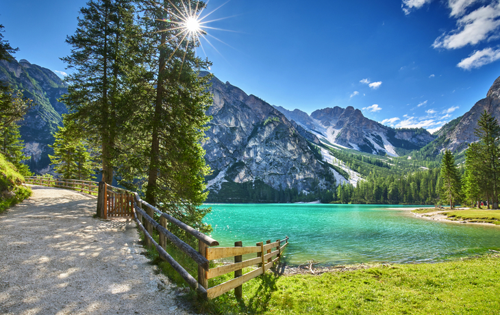Ein Bergsee mit türkisfarbenem Wasser, umgeben von Bergen und Bäumen.
