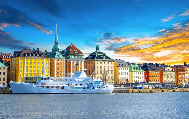 Bunte Gebäude am Wasser mit einem weißen Boot im Vordergrund.