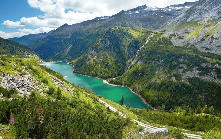 Bergsee in Gebirgslandschaft mit Wäldern und klarem Himmel.