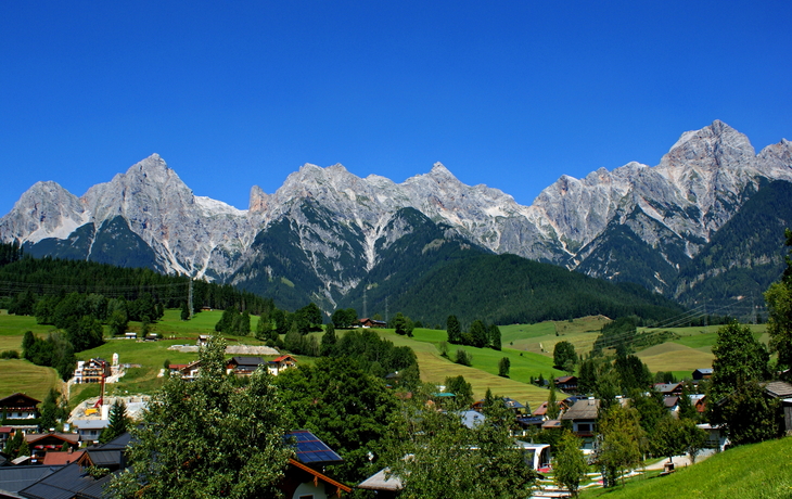 Berglandschaft mit Häusern und blauen Himmel im Vordergrund.