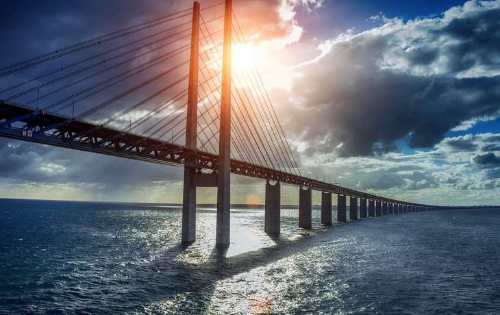 Lange Brücke über das Meer bei Sonnenuntergang mit Wolken am Himmel
