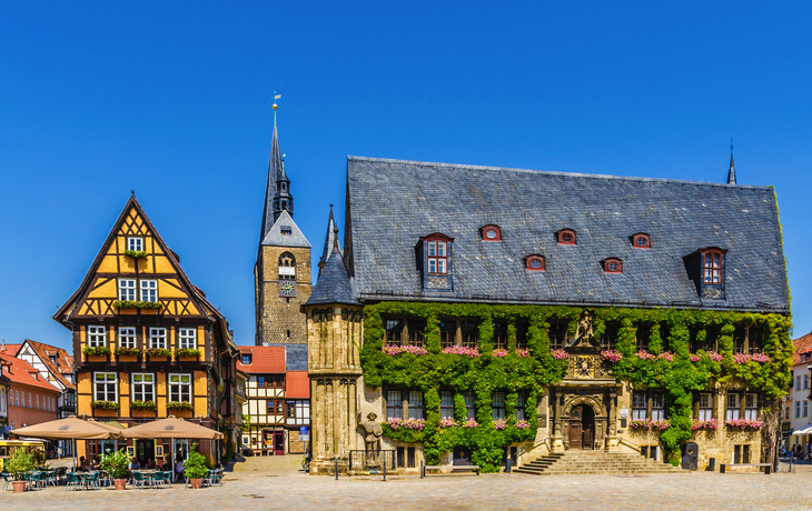 Historisches Rathaus und Fachwerkhäuser auf einem Platz bei blauem Himmel.
