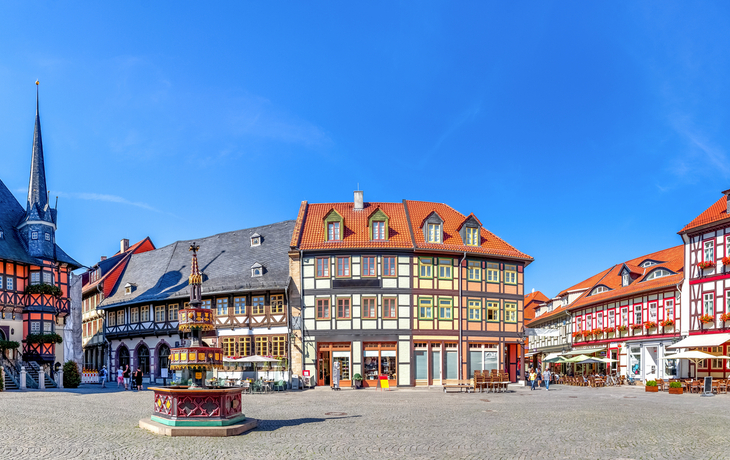 Mittelalterlicher Marktplatz mit Fachwerkhäusern und blauem Himmel.