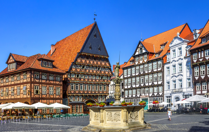 Historische Fachwerkhäuser mit Brunnen auf einem Platz.