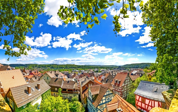Blick auf eine malerische Altstadt mit Fachwerkhäusern unter blauem Himmel.