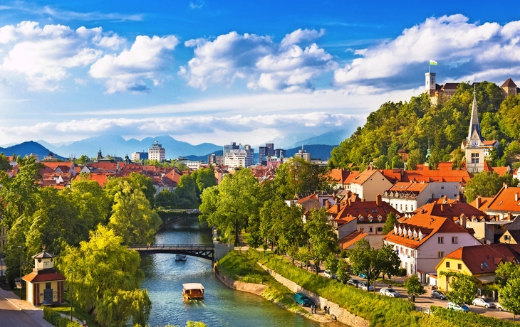 Stadtansicht mit Fluss, Brücke und historischen Gebäuden unter blauem Himmel