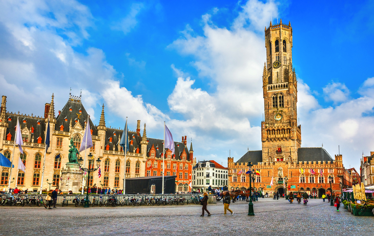 Historische Gebäude und Belfried auf einem Platz bei klarem Himmel.