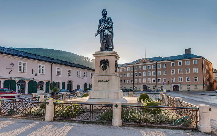 Statue von Mozart auf einem Platz in einer historischen Stadtumgebung.