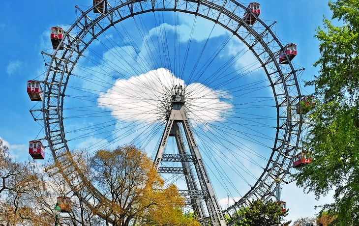 Riesenrad in einem Park mit blauem Himmel und Wolken im Hintergrund