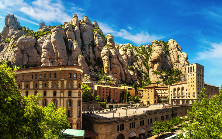 Blick auf Klostergebäude vor bizarren Felsformationen unter klarem Himmel.