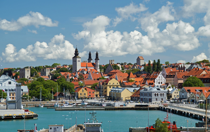 Küstenstadt mit bunten Häusern und Kirche unter wolkigem Himmel.