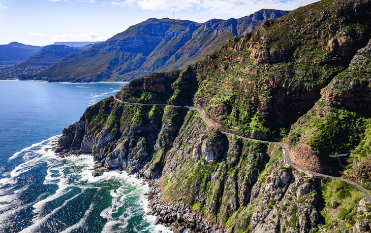 Küstenstraße entlang steiler Klippen mit Meer im Hintergrund.