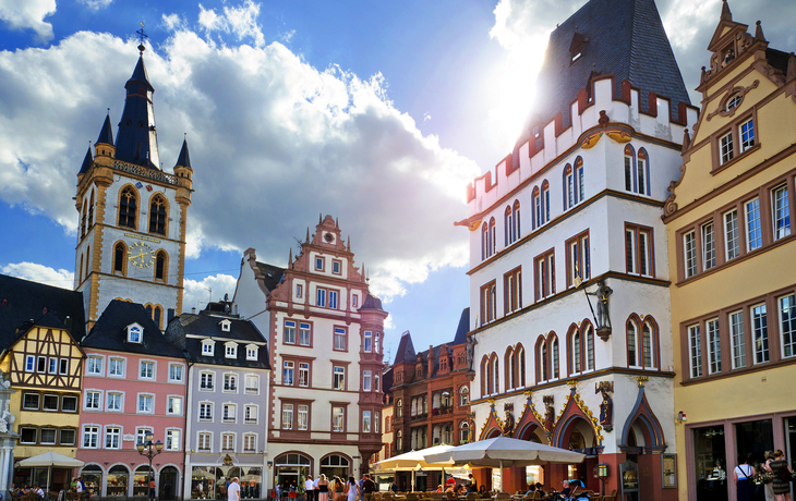 Historische Gebäude und Menschen auf einem Platz bei sonnigem Wetter.