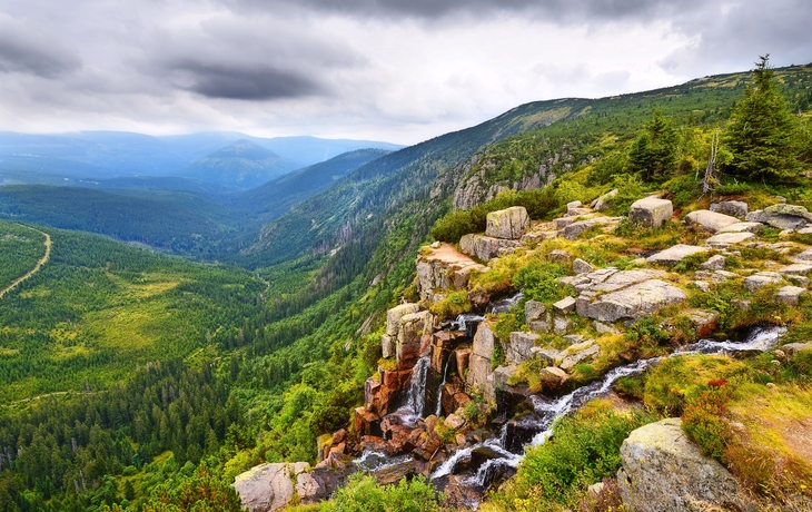 Berglandschaft mit Wasserfall und bewölktem Himmel