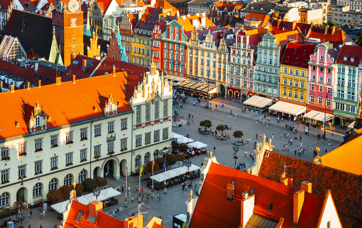 Luftaufnahme eines malerischen Platzes mit bunten Gebäuden und Menschen.