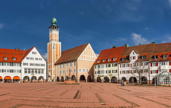 Weitläufiger Platz mit historischen Gebäuden und Turm im Hintergrund.