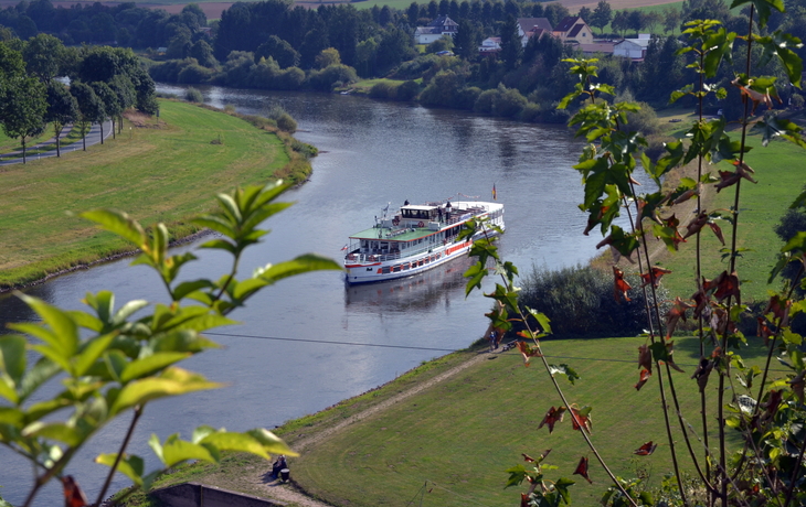 Ein Fluss mit einem Ausflugsschiff und Landschaft im Hintergrund