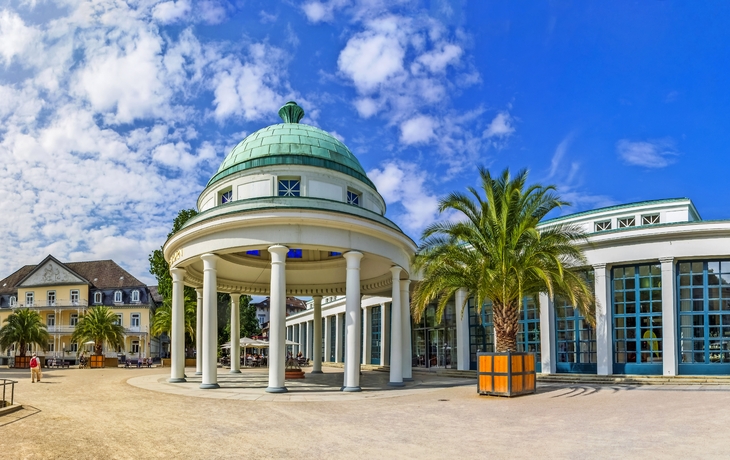 Runder Pavillon mit grüner Kuppel und Glasgebäude bei sonnigem Wetter.
