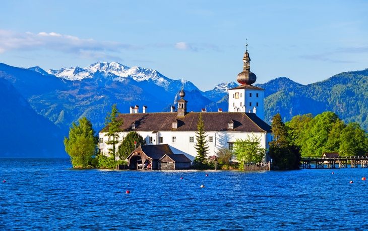 Historische Inselkirche auf See vor Bergkulisse.