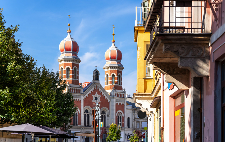 Blick auf Kirche mit Zwiebeltürmen in einer sonnigen Stadtstraße.