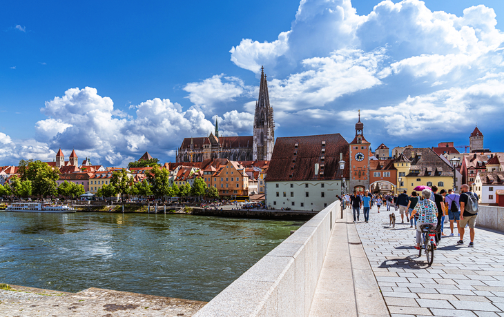 steinerne Brücke in Regensburg mit Blick auf den Dom St. Peter und die Donau bei sonnigem Wetter
