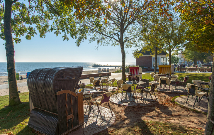 Café mit Strandkörben an herbstlicher Promenade am Meer.