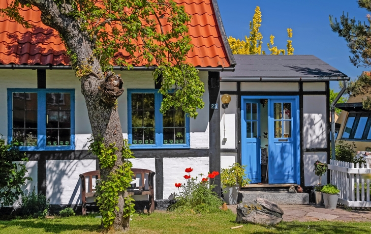 Fachwerkhaus mit blauem Türrahmen und Garten im Sommer.