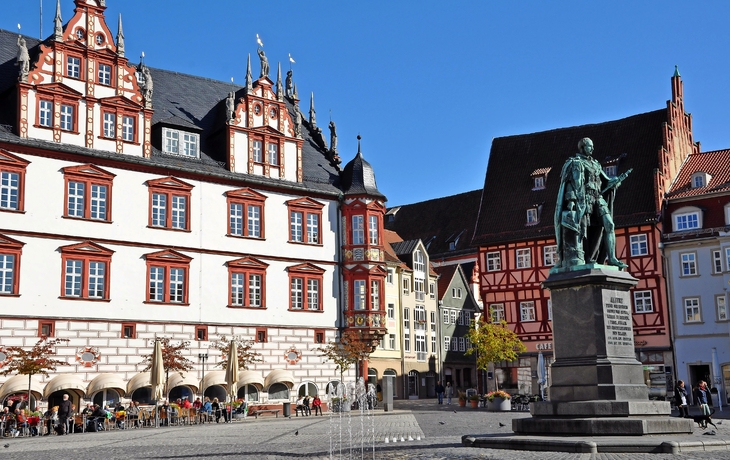 Stadtplatz mit historischen Gebäuden und Bronzestatue.