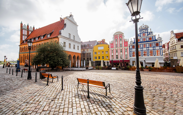 Historischer Marktplatz mit bunten Häusern und Straßenlaterne.