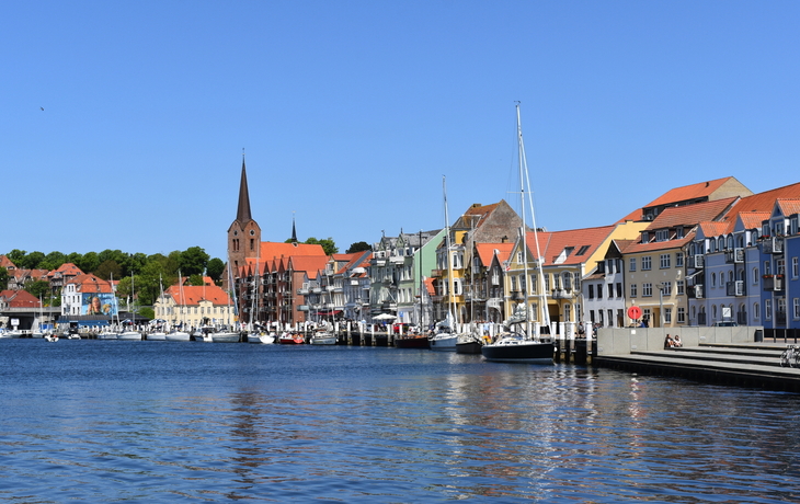 Hafen von Sønderborg in Dänemark, mit bunten Gebäuden und Segelbooten an einem sonnigen Tag.