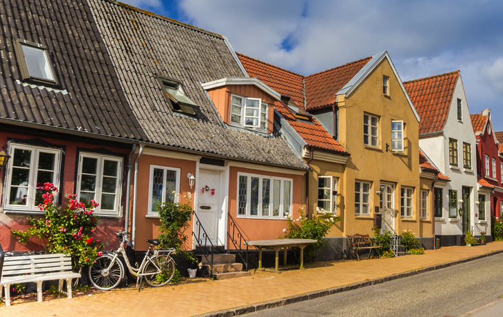 Reihe bunter Häuser in einer Straße bei sonnigem Wetter.