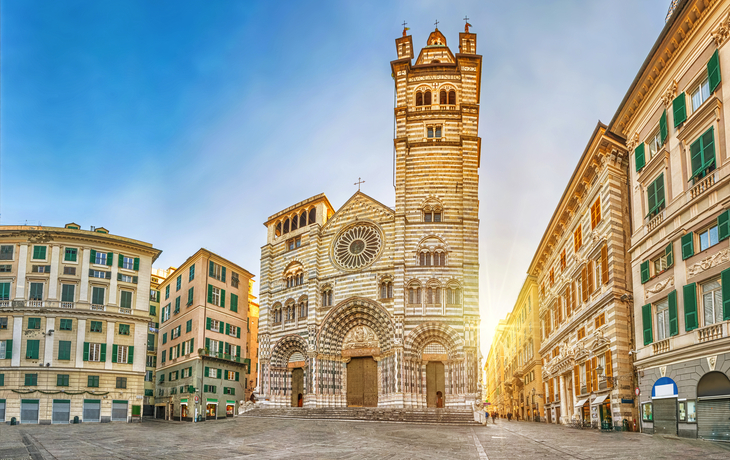 Historische Kathedrale mit weißen und grauen Streifen auf einem leeren Platz bei Sonnenuntergang.