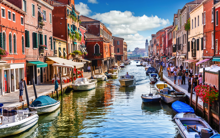 Kanal in Murano mit Booten und bunten Häusern bei Tag.